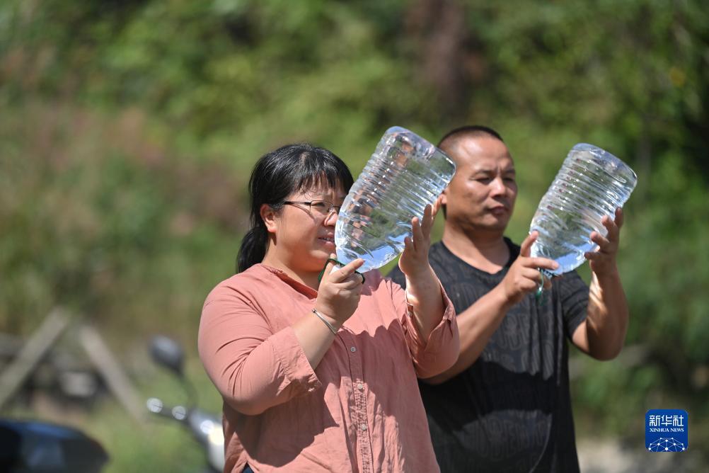 楊寧（左）在查看村民剛剛采集的水樣，為山泉水引水工程做準(zhǔn)備（10月8日攝）。新華社記者 黃孝邦 攝